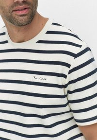 Stribet kortærmet t-shirt i navy og hvid. Har en rund halsudskæring og et lille broderet logo på brystet. Blødt, strukturelt stof.