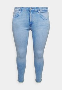 Jeans ajustados de mezclilla de color azul claro, con una cintura alta, cinco bolsillos y detalles de dobladillo deshilachado en los tobillos.