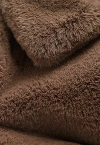 Brunt faux fur-stof med en blød, fluffy tekstur; har en tykk, kort pels med varierende længder for ekstra dybde og varme.