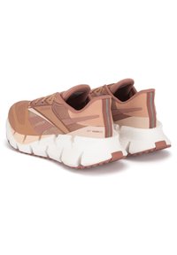 Ružové športové topánky s sieťovinovým zvrškom, špecifikované textúrovaným bočným panelom, polstrovanou bielou podrážkou a kontrastnými ružovými akcentmi.