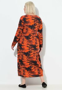 Maxikleid mit langen Ärmeln in Schwarz, Orange und rotem abstraktem Muster. Weicher Stoff mit einer entspannten Passform, tailliertem Bund und einfachem Rundhalsausschnitt.
