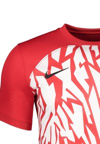 Rood sportshirt met korte mouwen, voorzien van een wit abstract patroon en een zwart Nike-logo op de linkerborst. Gemaakt van zachte stof.