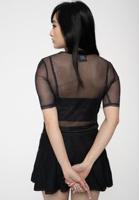 Black mesh top with short sleeves, semi-transparent design, and contrasting stitching. Paired with a black flared skirt.