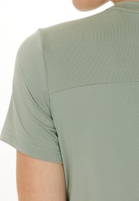 Ljust grön kortärmad skjorta med en mjuk textur, som har sömdetaljer över axlarna och en avslappnad passform.