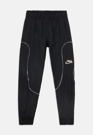 Pantalones jogger negros de Nike con cintura elástica, ribete blanco curvado, tobillos ajustados y un pequeño parche con el logo de Nike en la pierna derecha.