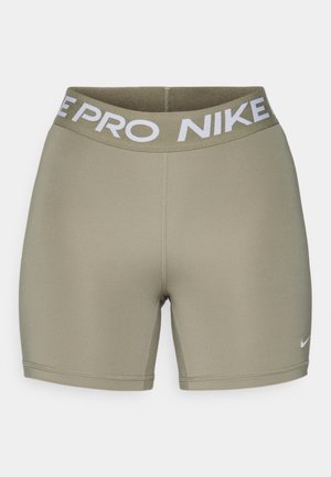 Olivno zeleni športni šort s širokim belim elastičnim pasom, na katerem je napis "NIKE PRO". Gladka, raztegljiva tkanina z detajli šivov.