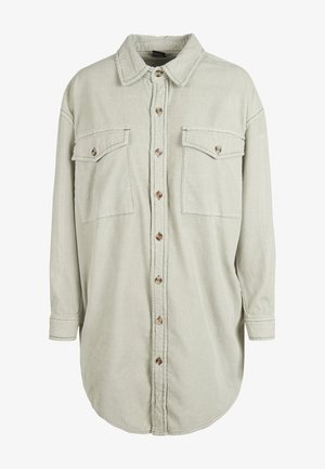 Svetlozelená kordová košeľa s dvoma náprsními vreckami, zapínaním na gombíky a golierom s preložením. Má dlhé rukávy a zakrivený lem.