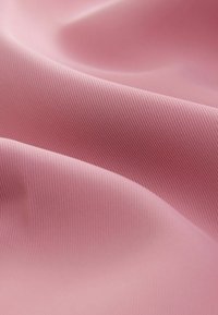 Texturovaná růžová látka s jemným žebrováním, která se vyznačuje měkkými sklady a hladkým povrchem, nabízící jemný lesk a jednotnou barevnost.