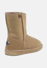 Botín de ante marrón con punta redonda, detalles de costura y un acento de logo en el lateral. Suela de goma que proporciona tracción.