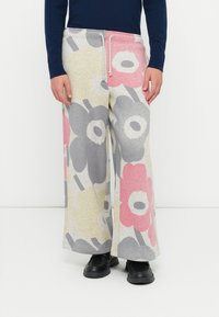 Kvetinové široké nohavice z mäkkej šedobielej látky s ružovými, šedými a žltými vzormi. Pás na šnúrku a jemná, textúrovaná látka. Čierna obuv.