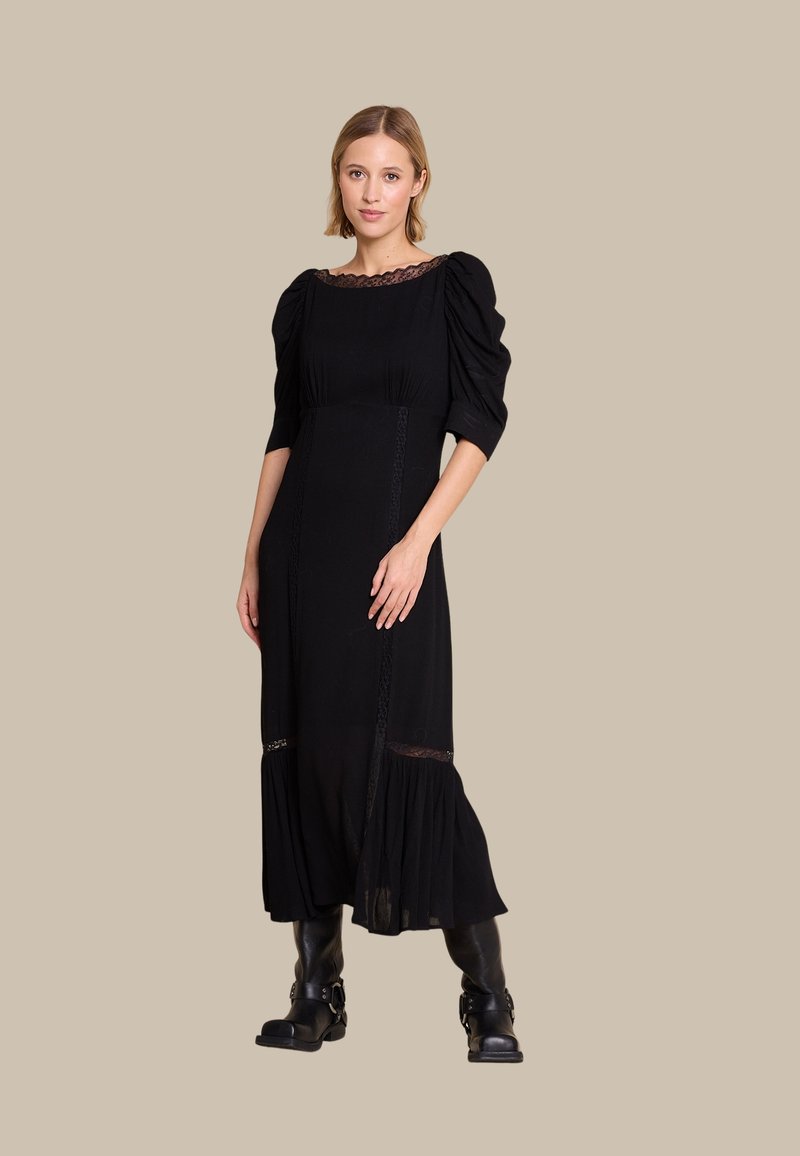 Svart kjole med pufferm, blonder trim på utringningen og lagdelt falm. Stoffet har en myk tekstur, og designet har intrikate blonder detaljer.