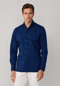 Camicia blu navy con bottoni in una leggerezza di cotone misto, caratterizzata da colletto a punta, maniche lunghe e bottoni a contrasto.