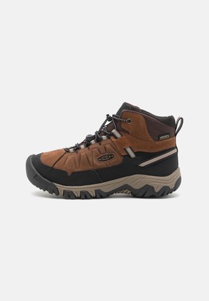 Herren-Wanderschuhe aus braunem Wildleder und schwarzem Gummi. Mittelhohe Ausführung, strukturierte Oberfläche, langlebige Sohle und verstärkte Ösen für die Schnürsenkel.