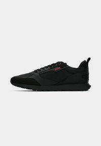 Black low-top sneaker with lace-up front, black sole, and red "HUGO" logo on side panel, designed for casual wear.