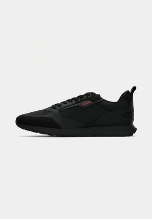 Black low-top sneaker with lace-up front, black sole, and red "HUGO" logo on side panel, designed for casual wear.