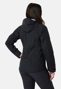 Sort vandtæt jakke med hætte, der har en tætsiddende pasform og justerbare manchetter. Glat tekstur med et strømlinet, minimalistisk design.