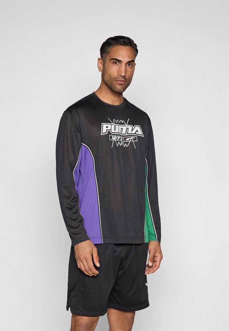 Μαύρο αθλητικό μπλουζάκι με μακριά μανίκια, με μωβ και πράσινα πλευρικά πάνελ. Διαθέτει λευκό λογότυπο Puma στο στήθος και υφή υφάσματος.