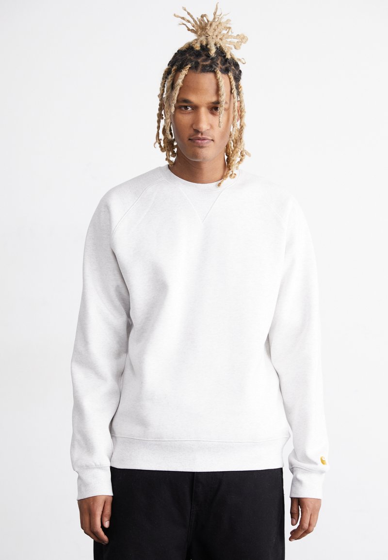 Lys grå sweatshirt med raglanærmer, ribstrikkede manchetter og kant. Har et lille gult logo ved manchetten. Blødt bomuldsblandingsmateriale.