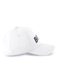 White baseball cap made of fabric, featuring a curved visor. The front displays bold black letters. Rear adjustable strap for fit.