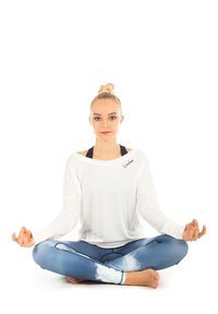 Hvid langærmet bluse med en afslappet pasform og sort logo, parret med blå leggings med et sky-mønster. Individ i en meditationspose.