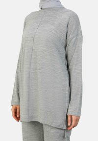 Light grey, long-sleeve top with a high neck, side slits, and subtle texture details. Loose fit, made from a soft, lightweight material.