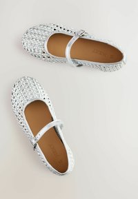 Scarpe basse intrecciate argento con punta arrotondata, cinturino alla caviglia e soletta liscia color tan. Presentano un intricato motivo a incrocio sulla parte superiore.