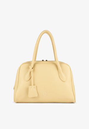 Żółta skórzana torebka o teksturowanej powierzchni, z dwoma zaokrąglonymi uchwytami oraz małą ozdobną zawieszką. Na przodzie subtelne tłoczone logo.