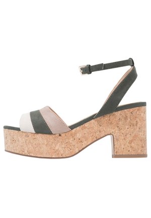 Sandały na platformie z odkrytymi palcami i koturnem z korka. Posiadają zielone i beżowe paski ze zamszu oraz regulowany pasek na kostkę.