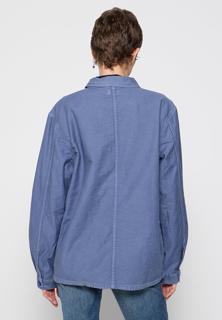 Blaue Chambray-Hemd mit Button-Down-Kragen, langen Ärmeln und geradem Schnitt. Verfügt über eine mittige Naht und verstellbare Manschetten.