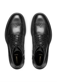 Scarpe brogue in pelle nera con perforazioni decorative, punta rotonda, design con lacci e cerniera laterale. Presentano una texture liscia e una soletta imbottita.