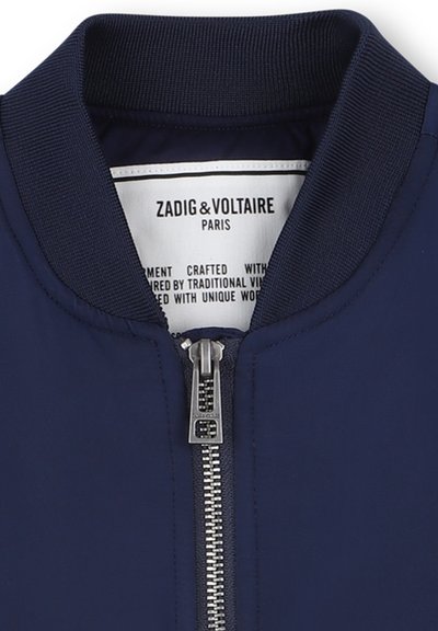 Marine bomberjack met een geribbelde kraag, voorzien van een zilveren rits en een label dat het merk, Zadig & Voltaire, aan de binnenkant aangeeft.