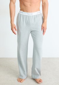 Helle graue Baumwoll-Loungehosen mit einem weißen elastischen Bund, der das Logo "Calvin Klein" trägt, entworfen für Komfort und einfaches Tragen.