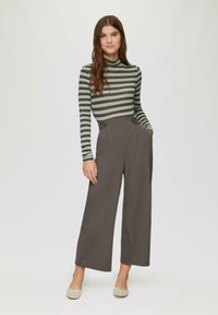 Gestreepte lange mouwen top in grijs en groen, gecombineerd met hoge, wijde grijze broek met knoopaccenten en zijzakken.