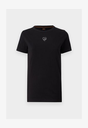 Črna bombažna majica s krožnim izrezom, kratkimi rokavi in belo grafiko srca na prsih. Preprost, neopazno oblikovan dizajn.