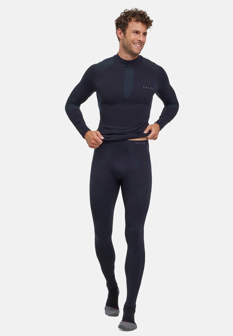 Ensemble de vêtements de sport masculin en bleu marine, comprenant un haut ajusté à manches longues et un legging avec des accents texturés subtils. Fabriqué à partir d'un matériau extensible.