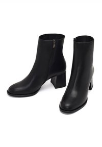 Bottines en cuir noir avec un bout carré, une fermeture éclair sur le côté et un talon épais. Texture lisse et design minimaliste.