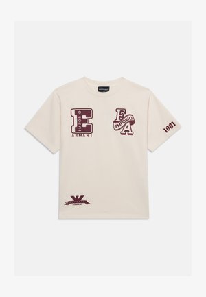 Beige t-shirt med vinrøde Emporio Armani-logoer på brystet, ærmet og nederste kant, med bogstaverne E og A og tallet 1981 på ærmet.