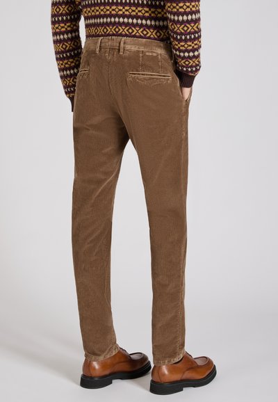 Brązowe spodnie z korduroju o prostym kroju. Charakteryzują się wyraźną teksturą i tylnymi kieszeniami. Połączone z brązowymi skórzanymi butami.