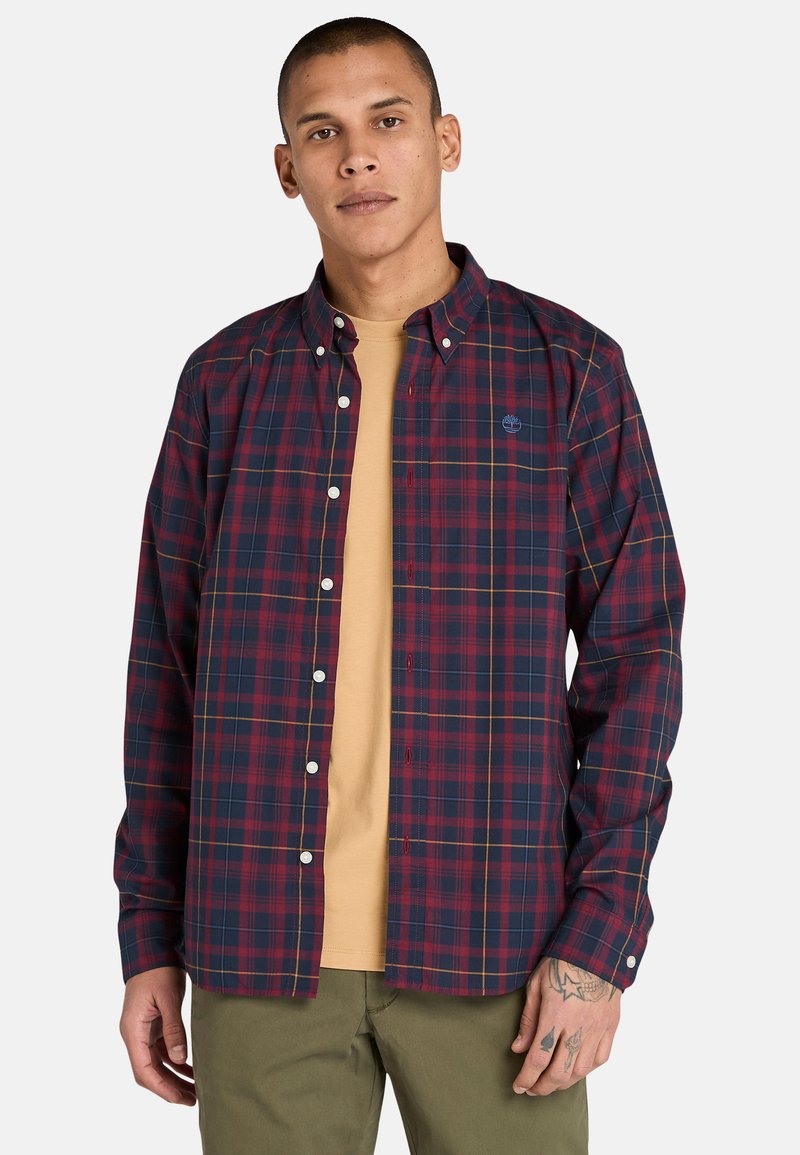 Camisa de cuadros con botones en tonos navy, rojo y amarillo; material de algodón; cuenta con un cuello clásico y un logo visible en el pecho.