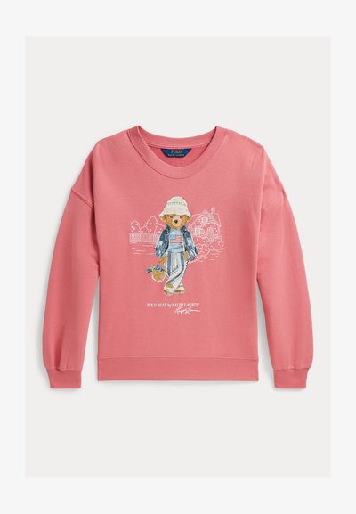 Ροζ φούτερ με μια αρκούδα που φοράει καπέλο, τζιν μπουφάν, ριγέ παντελόνι, κρατώντας ένα καλάθι, με σκίτσα σπιτιού και κήπου στο φόντο.