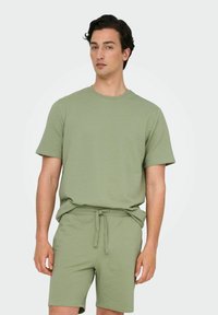Grøn t-shirt med waffle-struktur og korte ærmer samt matchende shorts. Shortsene har en elastisk talje og justerbar snor.