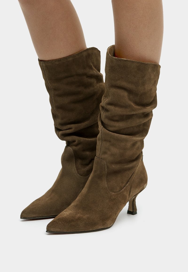 Brown suede ankle boots with slouchy upper, pointed toe, and low kitten heels. Features a smooth texture and subtle stitching detail.