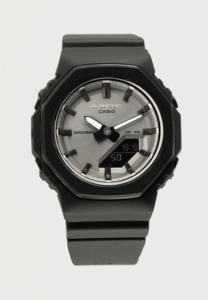 Black Casio G-Shock wristwatch with analog-digital display, silver dial, and black resin strap showing time 10:10:50.