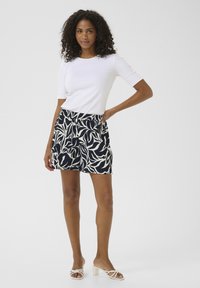Top bianco a maniche corte abbinato a pantaloni corti blu navy con un motivo a foglia bianca. Tessuto morbido con vita elastica, vestibilità casual. Leggibilità chiara delle gambe.