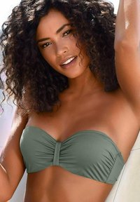 Top bikini bandeau verde realizzato in tessuto morbido con dettagli arricciati al centro. Il design è senza spalline, evidenziando uno stile minimalista.