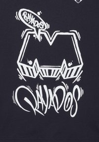 La impresión gráfica en tela oscura presenta letras blancas en negrita, incluyendo formas estilizadas de "M" y la palabra "RAYADOS" en un diseño dinámico.
