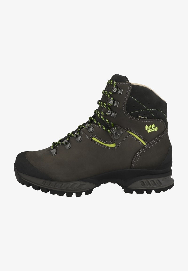 Bota de caminhada castanha com detalhes em verde, parte superior em couro, biqueira em borracha, ganchos metálicos para os cordões e sola texturizada para melhor tração.