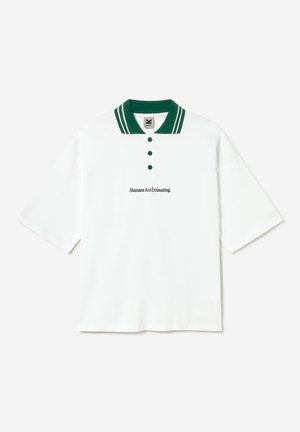 Polo blanc avec col et boutons verts, manches courtes, et texte brodé "Humans Are Exhausting" sur la poitrine.