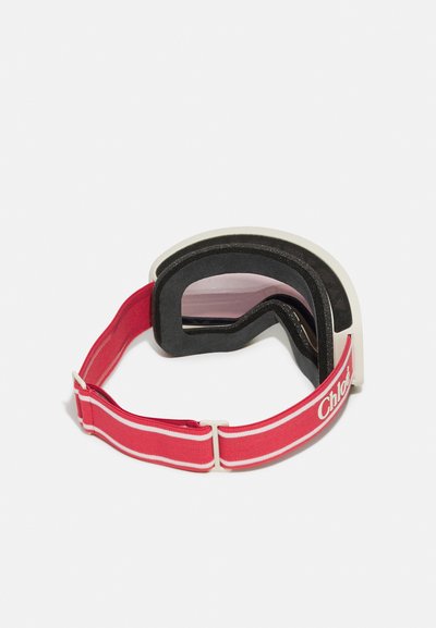 Skidglasögon med en vit ram, mörk skumvaddering och röd justerbar rem med en diskret logotyp. Linserna är lätt tonade i rosa.