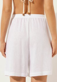 Shorts en lin blanc avec une taille élastique, texture lisse et ourlet roulé. Coupe légèrement ample pour le confort et la respirabilité.
